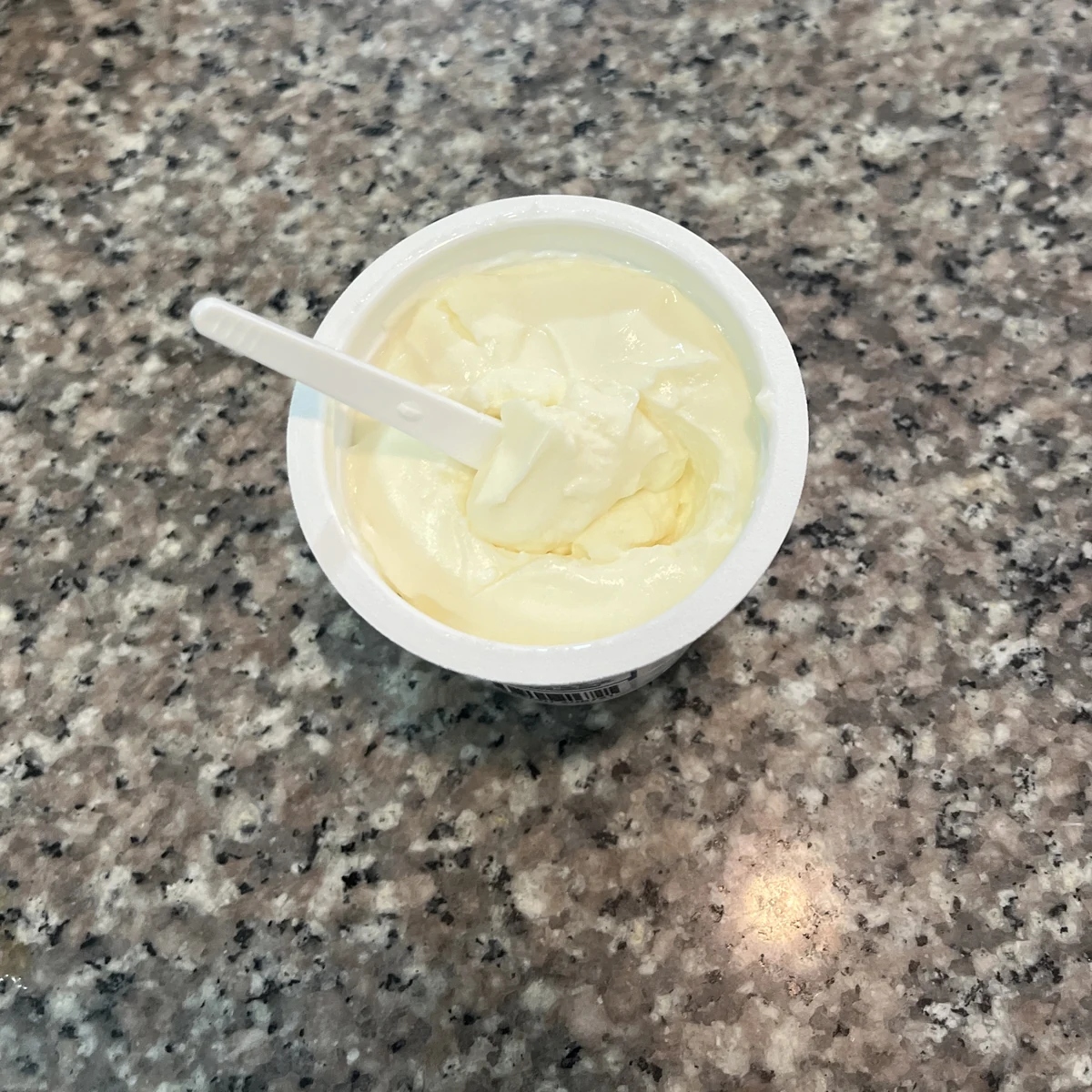 Fotografía real de la densidad del yogurth griego KIKE recién abierto con cuchara firme